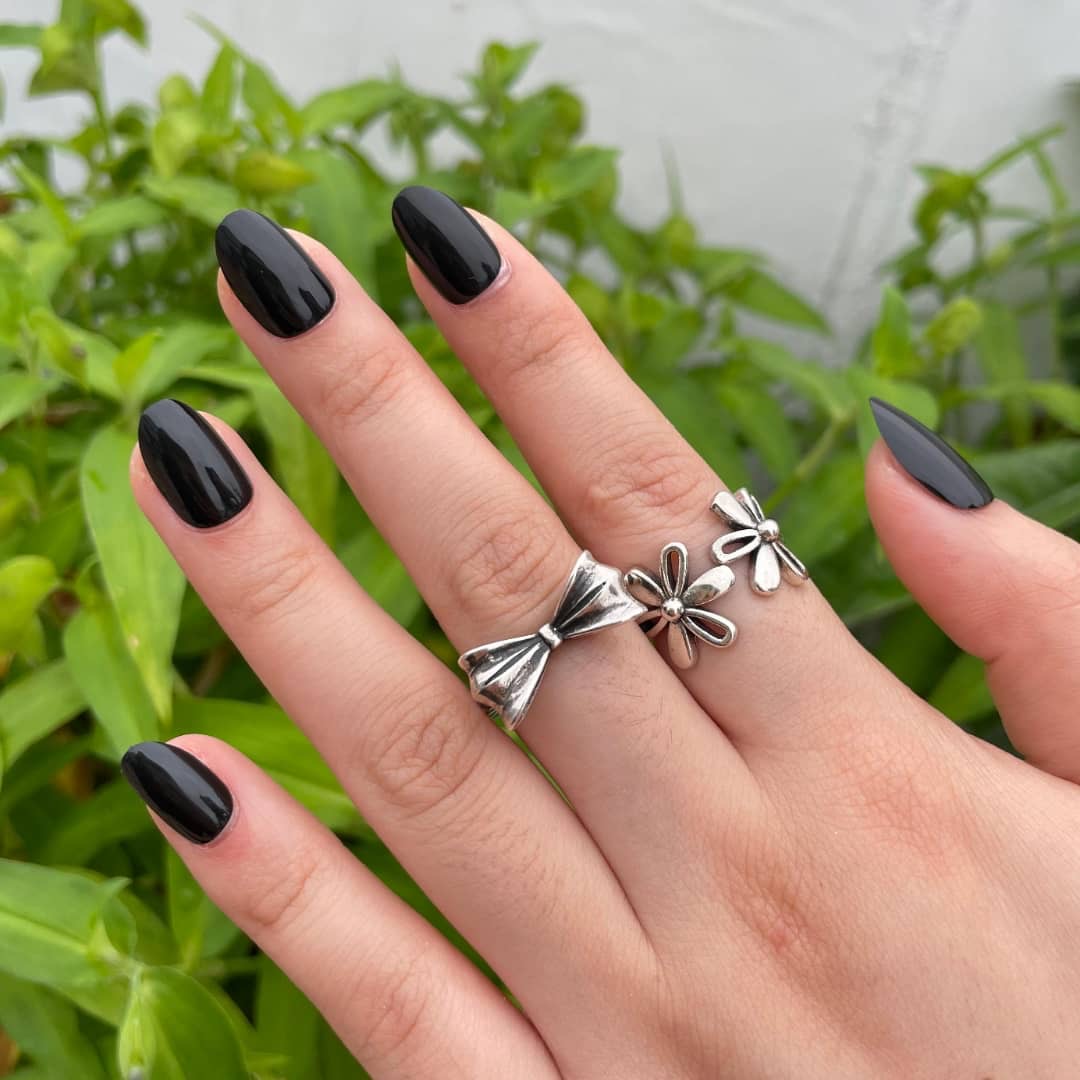 Blackout glossy black press-on nails hand shot with greenery – Impress Me Nails Lebanon
