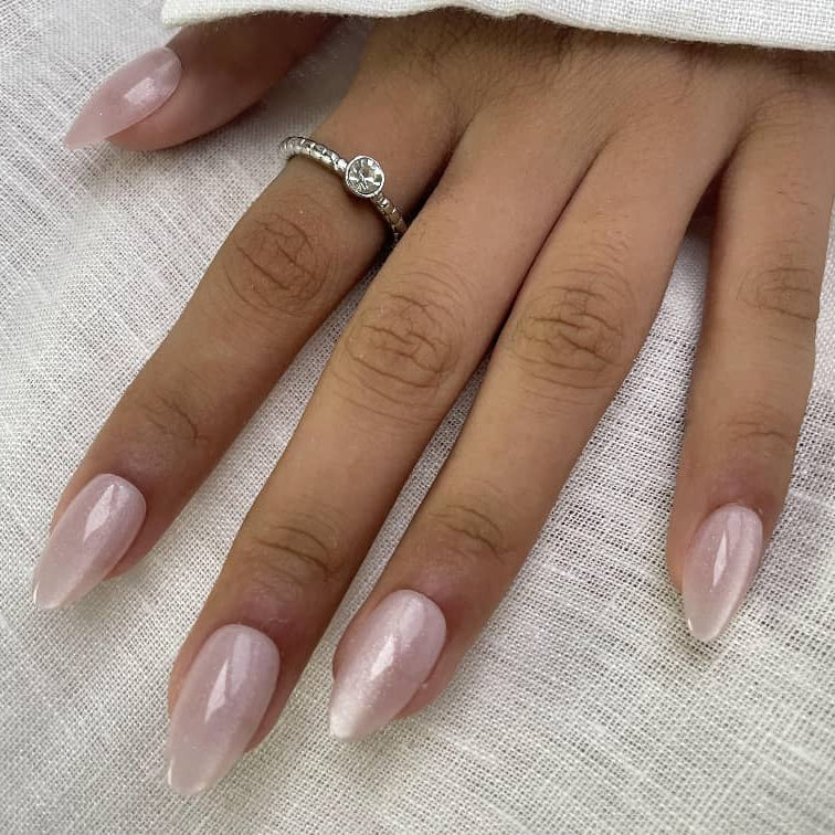 Close-up of hand with Cloud Kiss soft pink shimmer press-on nails in almond shape