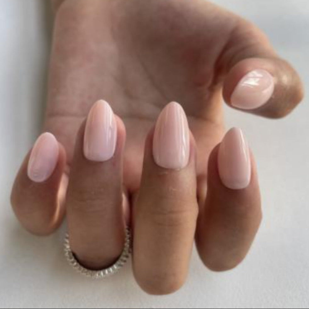 Hand wearing glossy nude press-on nails called Silk Nude with a soft peach finish