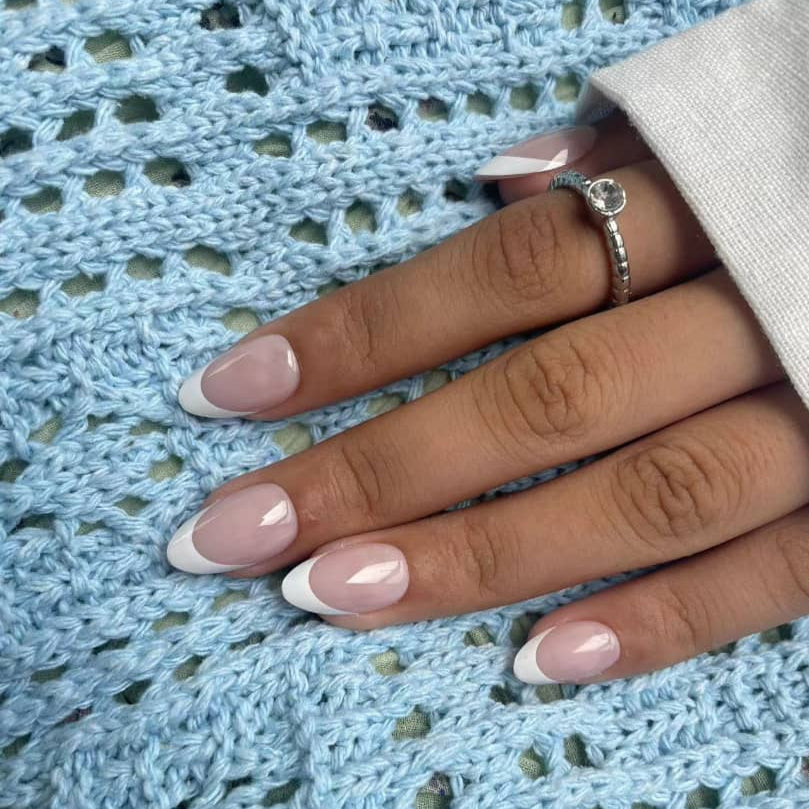 Hand showing glossy French Lady white tip press-on nails in classic oval shape