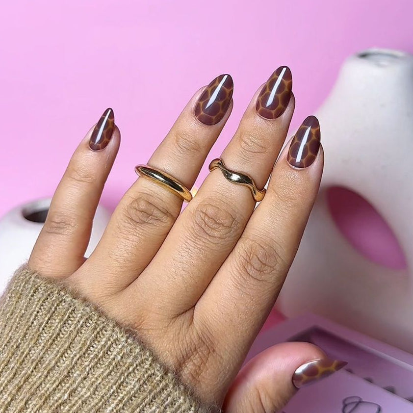 Close-up of Impress Me Toffee Hive giraffe-style press-on nails in Beirut – trendy brown patterned nails for fall